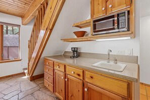 Small kitchenette with a sink, classic coffee machine, microwave, and basic kitchen utensils.