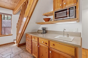 Small kitchenette with a sink, classic coffee machine, microwave, and basic kitchen utensils.
