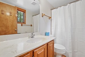 The bathroom features a shower/tub combination, ample cabinet space, and beautiful white stone countertops.