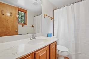 The bathroom features a shower/tub combination, ample cabinet space, and beautiful white stone countertops.