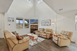 2 leather sofas and a leather lounge chair surrounding a lovely wooden coffee table. A smart, flat screen TV with HD antenna rests above the gas fireplace
