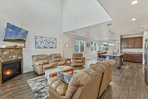 2 leather sofas and a leather lounge chair surrounding a lovely wooden coffee table. A smart, flat screen TV with HD antenna rests above the gas fireplace