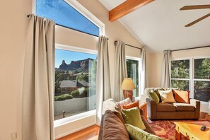 Natural light floods the open-concept living area, highlighting the soaring ceilings and comfortable furnishings.