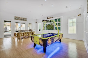 1st Floor - Game room with air hockey, custom arcades, 4K Smart TV, dining table, and a wet bar complete with mini fridge, ice maker, sink, and microwave