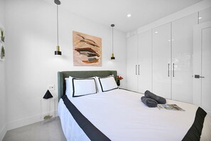 Minimalist bedroom with ample storage, modern lighting, and calming decor.