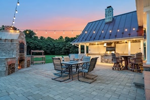 Just steps away from the large indoor kitchen/dining area, there is a beautiful outdoor kitchen space with a working charcoal grill.