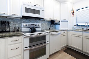 Modern kitchen fully equipped with sleek appliances and stylish backsplash.