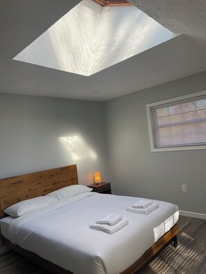 Queens size bedroom with sky view window…
