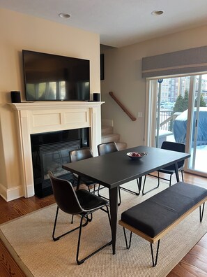 Main floor great room with dining table, fireplace and TV.