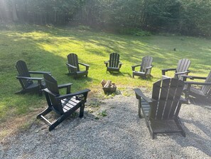 Wood-burning firepit with surrounding Adirondack chairs.