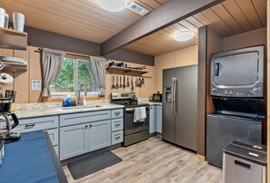 Kitchen w/ stove/oven, fridge/freezer, microwave, washer/dryer.