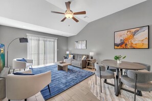 The spacious living room features a dining table, with a smart TV for relaxation, with privacy blinds overlooking the backyard.