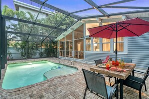 Screened Pool and patio with an Al Fresco dining table and the Lanai in the distance at Twilight