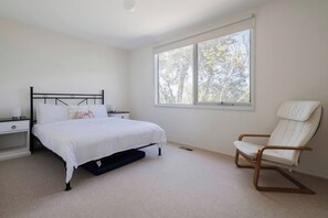 Find tranquillity in this light-filled second bedroom with a cosy queen bed, perfect for a peaceful retreat.
