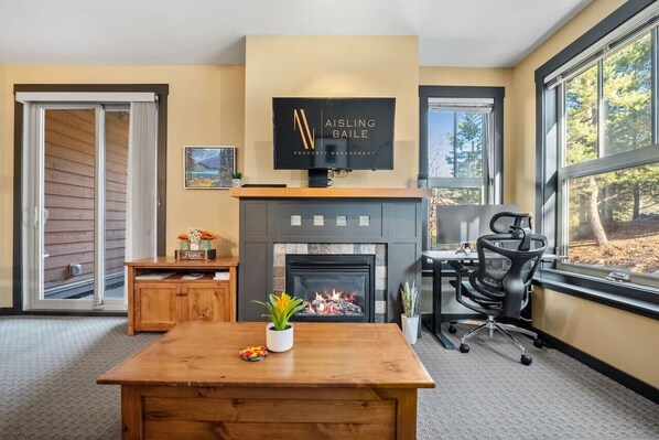 Living room of Snowy Lodge with a gas-lit fireplace, queen pull-out bed, smart TV & a dedicated workstation.