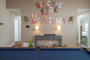 Spacious living room with large smart tv, pool table, games, fire place, etc