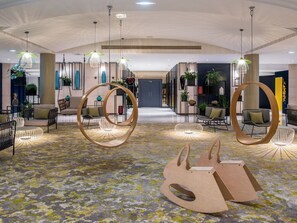 Step into a playful, modern lounge area with comfortable seating and unique swings, inviting you to relax and socialize in style.