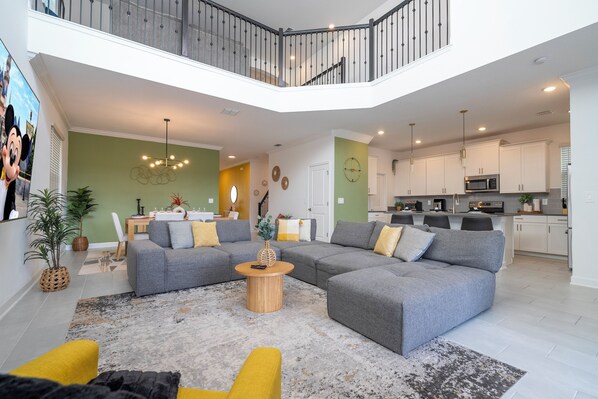 The spacious open living area boasts a modern design with a large, comfortable couch and a big-screen TV, creating the perfect space for relaxation and entertainment. Natural light fills the room with pool views,  truly refreshing and inviting atmosphere.