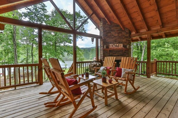 Over-sized back deck with a lake view, seating and a wood-burning fireplace 