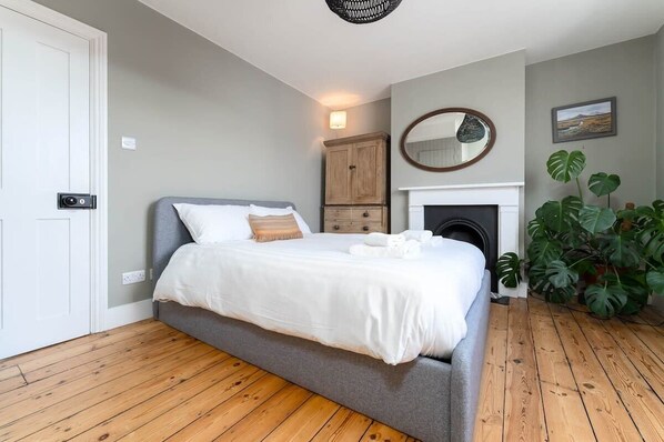 Master bedroom with king size bed and plenty of fresh bed linen and towels. A light contemporary room with wooden floorboards and original fireplace (not in use). 