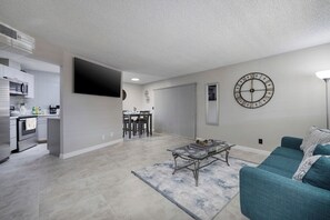 Family room with a large flat screen  mounted TV and a comfy couch to relax and enjoy a movie in between the hussle.  