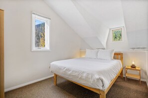 Loft/bedroom with a queen bed, twin-over-twin bunk bed, ceiling fan, wardrobe & a portable fan/heater.