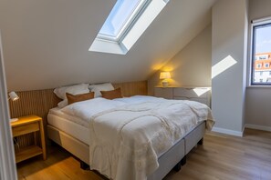 This elegant attic bedroom features a plush double bed, warm lighting, and a skylight for dreamy stargazing nights near the coast.