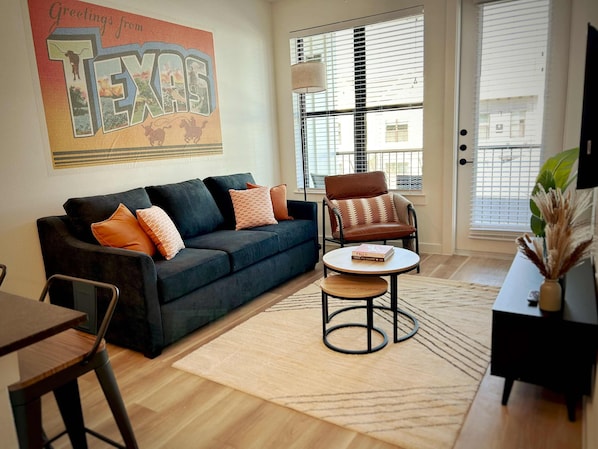 Sun soaked living area with smart TV, access to patio, and a queen pullout couch