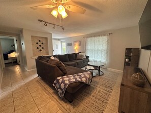 Livingroom with a large L-shaped couch and a 75'' TV.