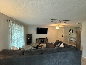 Livingroom with a large L-shaped couch and a 75'' TV.
