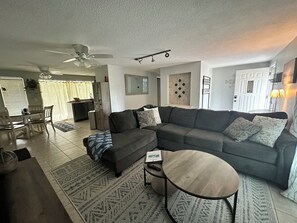 Livingroom with a large L-shaped couch and a 75'' TV.