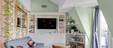 Open plan living room and kitchen with French doors opening onto the balcony.