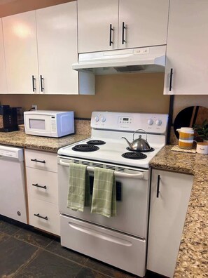 Kitchen includes full fridge, stove, microwave and coffee machine.