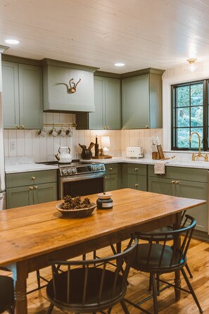 The kitchen is fully stocked with all stainless appliances and open shelving.