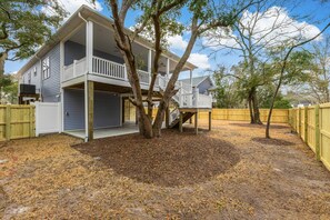 This fenced-in backyard features stairs leading up to the balcony with ample seating, perfect for enjoying the fresh air.