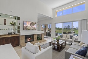 Living room: Spacious area with fireplace, comfortable seating, TV, and views of the outdoor patio.