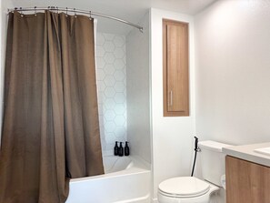 Relax and refresh in our well-appointed bathroom featuring a bathtub, blowdryer, and complimentary essentials like toothpaste, towels, lotion, shampoo, conditioner, body wash, and hand soap.