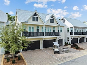 A stunning coastal-style townhome featuring modern architecture, a spacious driveway, and premium amenities.
