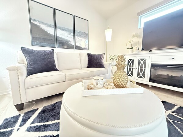 Cozy living room with electric fireplace, Smart TV, and comfy sofa.
