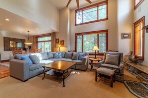 Living room has tall vaulted ceilings and picture windows overlooking the pine tree forest and golf course.