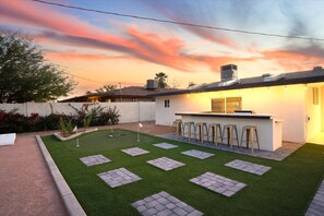 The perfect combination: a stylish outdoor bar and a spacious backyard with putt-putt and cornhole for endless entertainment.