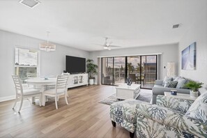 Beautiful, bright, open living space with pool view. Living room features comfy seating and 65-inch Roku TV. Dining table seats 4