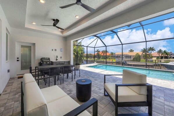 The best of Florida outdoor living. Lanai with outdoor kitchen overlooking the sparkling private pool and canal