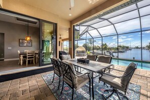 Large outdoor living space with sparkling, private pool &amp; spa overlooking the water. Outdoor living space also includes a dining table for 6, sun loungers, outdoor seating, BBQ grill, and two 55-inch Smart TVs