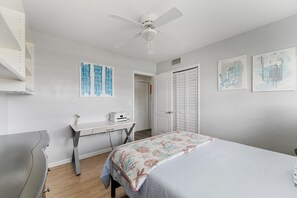 Relax in the serene queen bedroom featuring coastal-inspired bedding, modern artwork, and ample storage. A sleek desk offers a functional workspace, making this room perfect for both leisure and productivity. Bright and airy, it’s a retreat you’ll love.