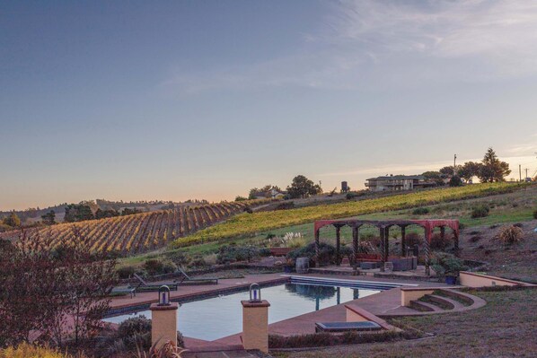 A breathtaking view of the estate, featuring rolling vineyards, a sparkling pool, and the natural beauty of wine country.