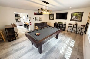 The game room offers a pool table, futon,  pub table, bar area, and a smart TV.