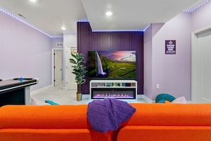 Fun-filled basement game room featuring a 75-inch TV, a cozy fireplace, and a sleeper for extra comfort and convenience.