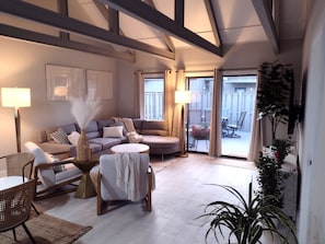 Newly furnished living room with stylish coastal decor, a comfortable sectional sofa, large flat-screen TV, and bright natural light—ideal for relaxing at Hilton Head Hideaway.