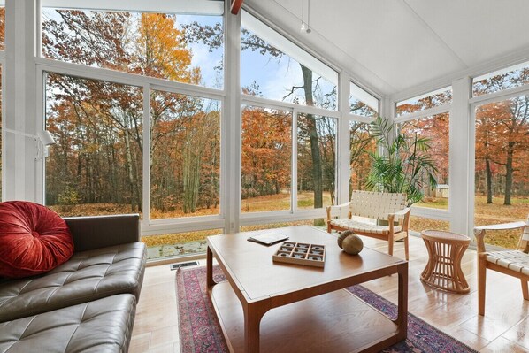 Bask in the tranquility of nature from this bright, glass-walled living room. Perfect for reading a book or simply relaxing and soaking in the serene surroundings.